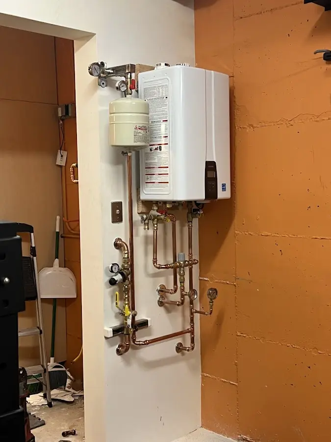 Plumbing technician inspecting water heater connections in Elba